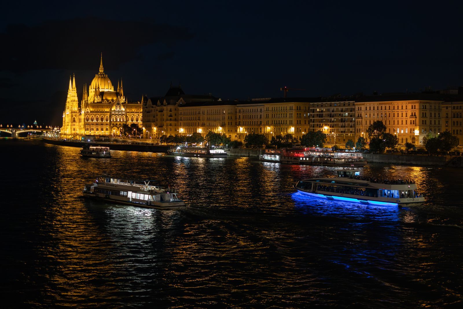 Budapest Parliament lit up at night above boats on the Danube, the kind of sailing shoppers watch for the best Black Friday river cruise deals